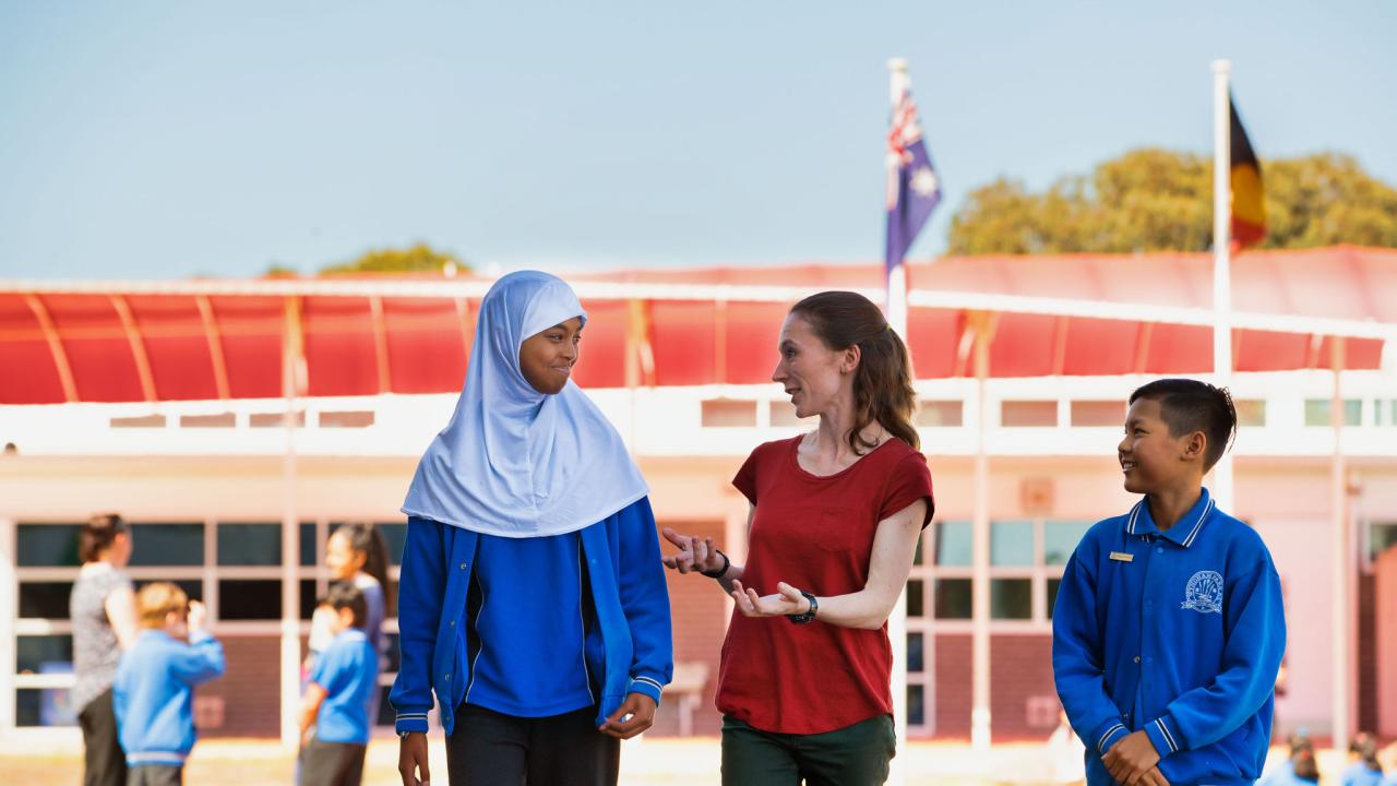 Teacher speaking with primary students outside