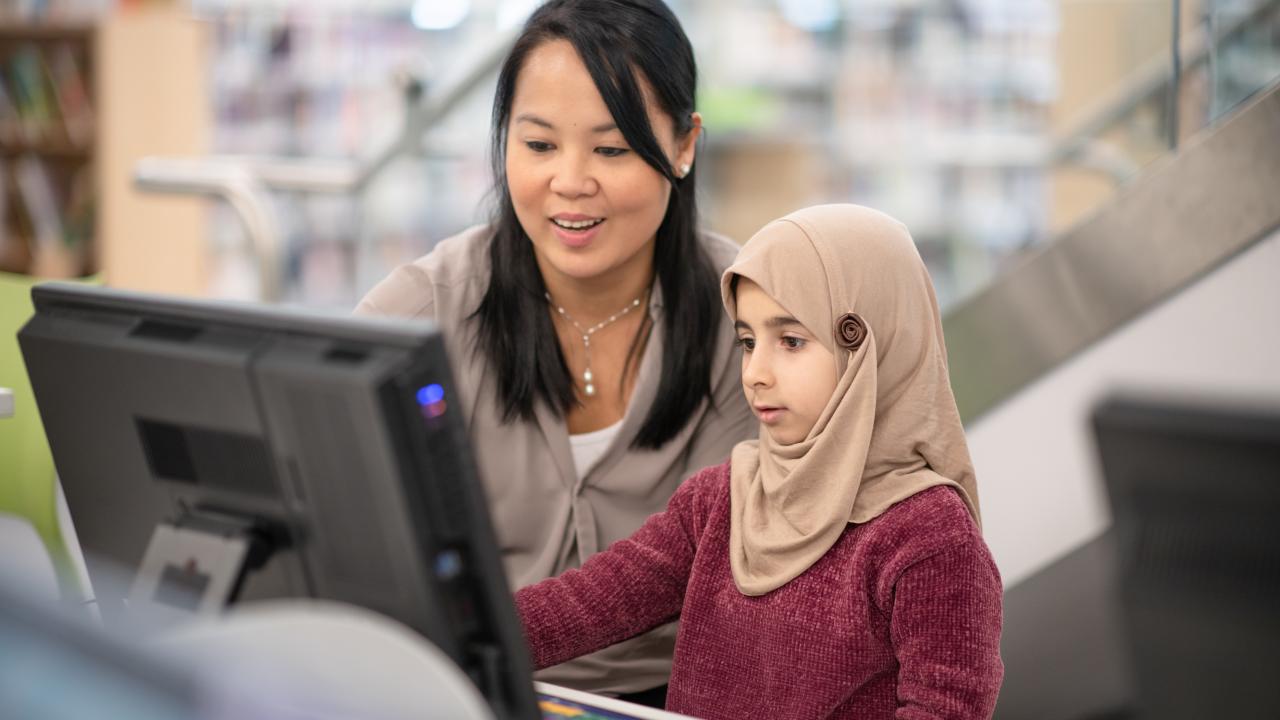 Teacher working with primary student in front of computer