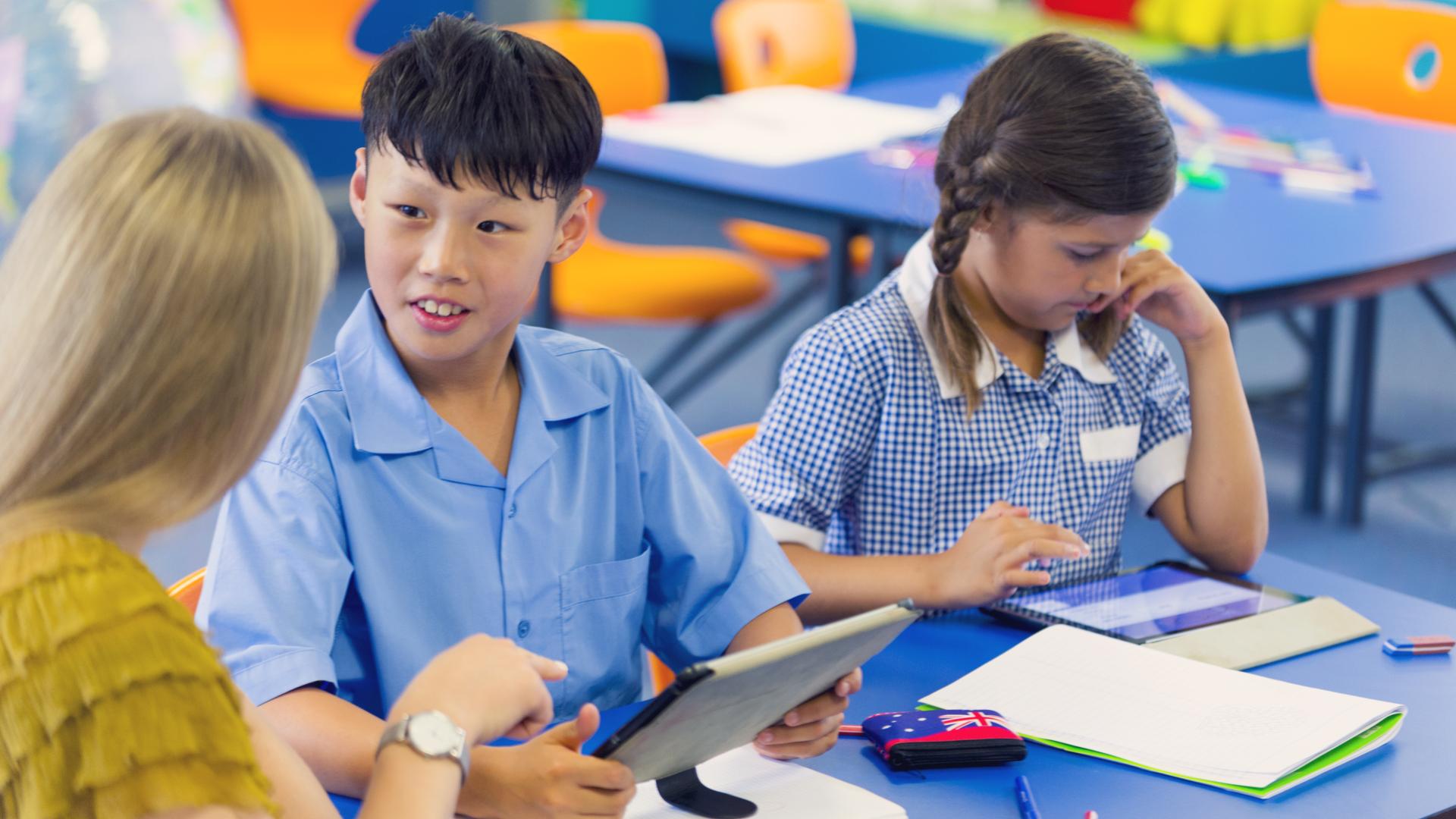 teacher with 2 primary students at desk